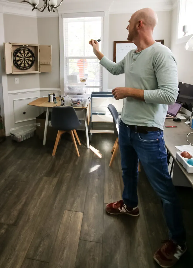 Throwing darts at DIY dartboard cabinet
