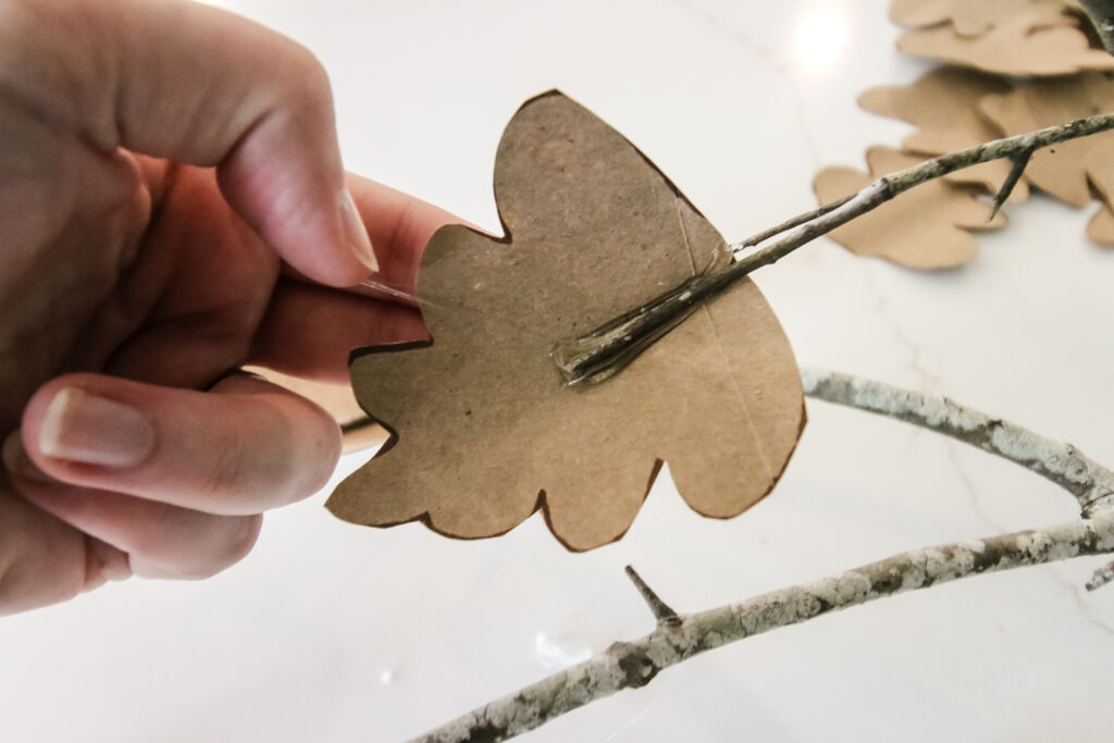 gluing brown paper leaves to branches