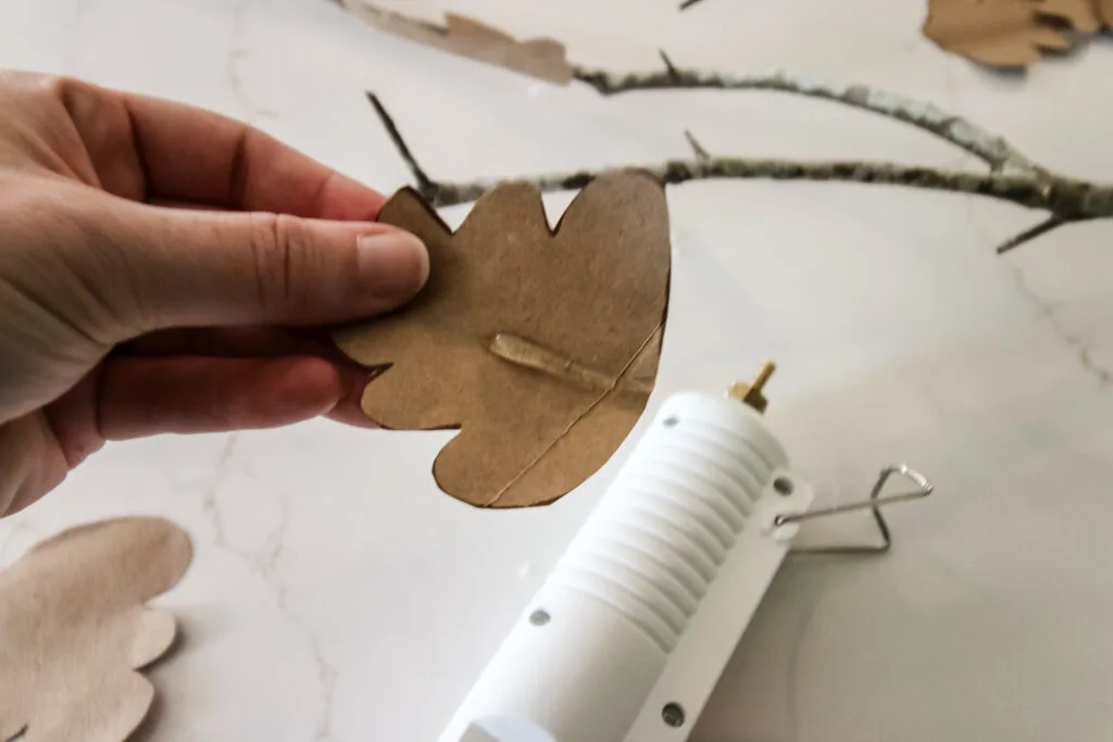 gluing brown paper leaves to branches