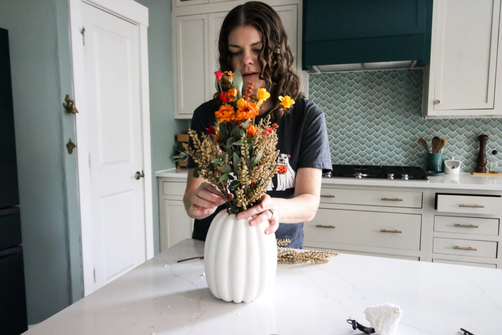 adding flowers to a DIY pumpkin vase