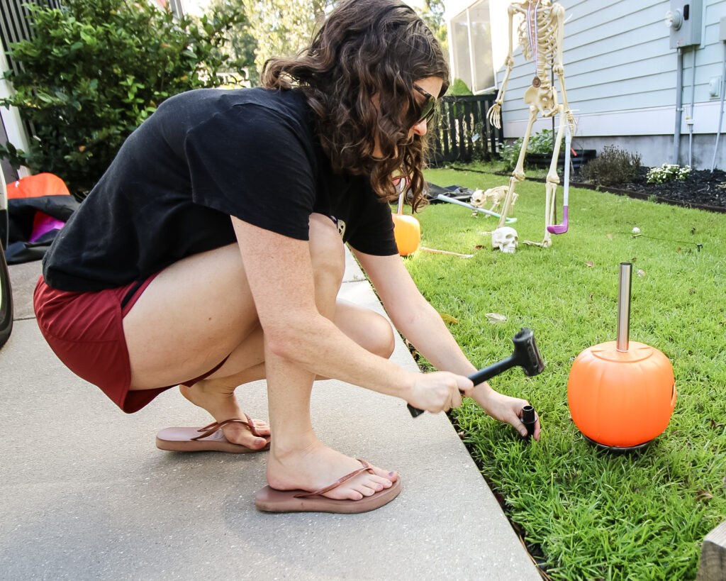 hammering a stake into the ground for pumpkin solar lights