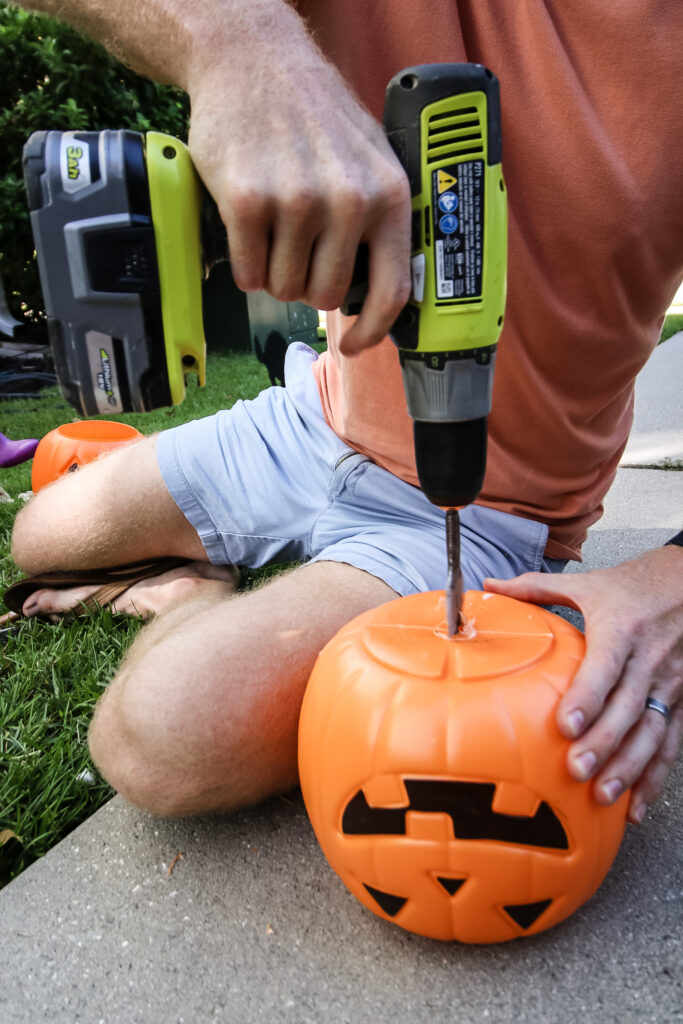 drilling a hole into a plastic pumpkin bucket