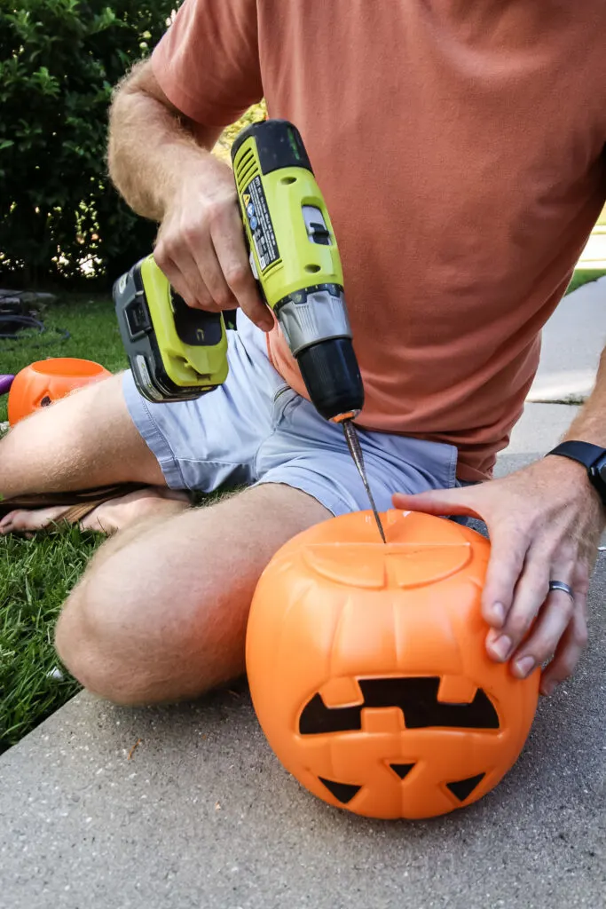 drilling a hole into a plastic pumpkin bucket