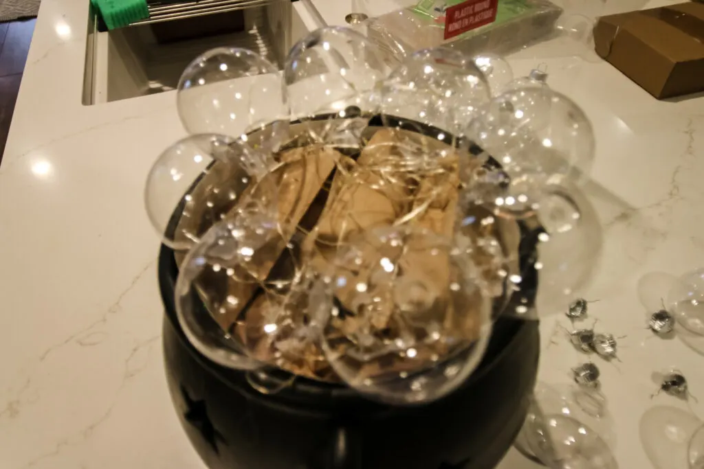 adding clear ornaments to a cauldron for halloween