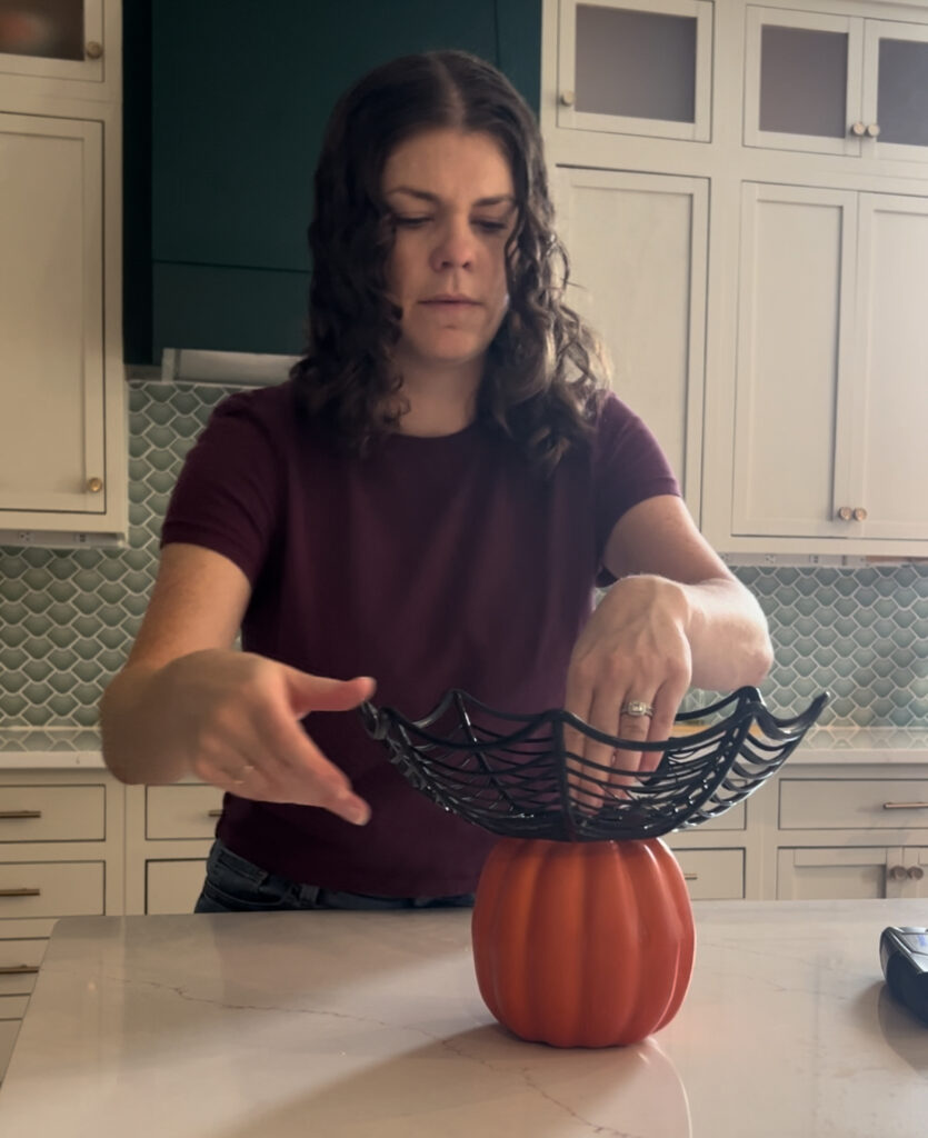 pressing hot glued bowl into a pumpkin top