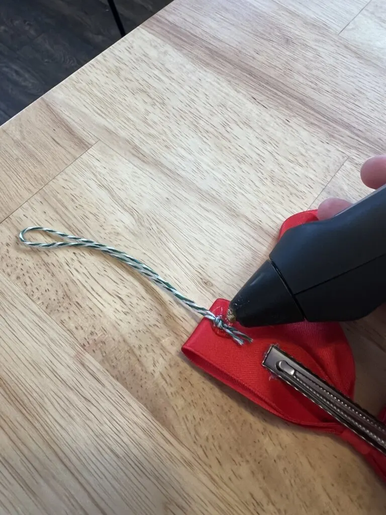 glueing loop of twine onto red bow garland