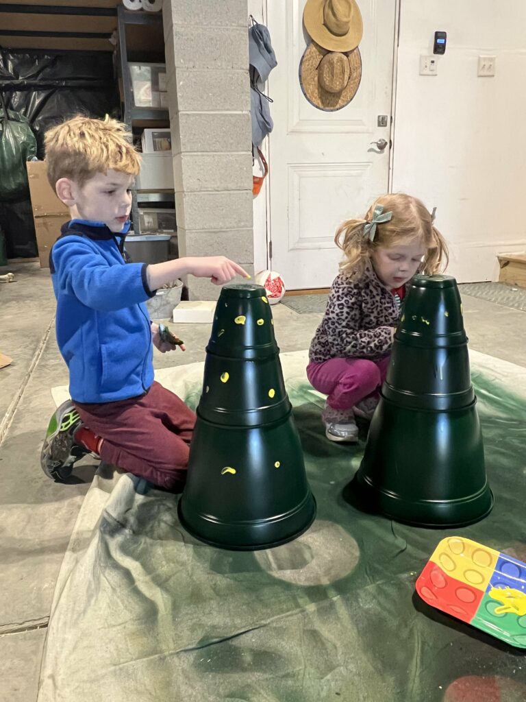 kids painting fingerprints on plastic pot christmas tree