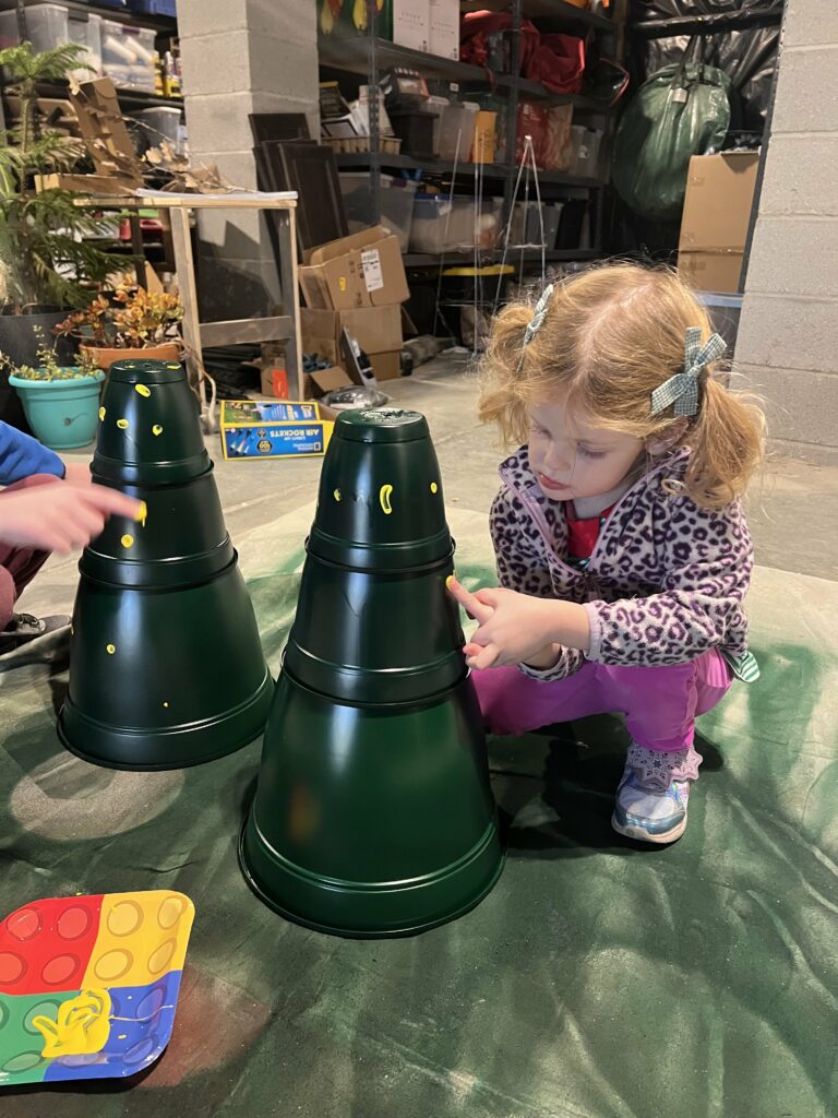 kids painting fingerprints on plastic pot christmas tree